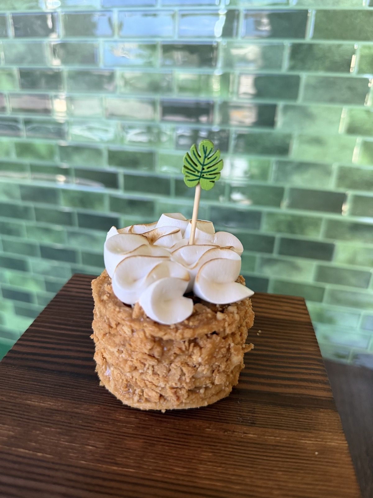 Dolce Lava, crumbly crust layers with dulce de leche under torched meringue petals, on a dark wood block