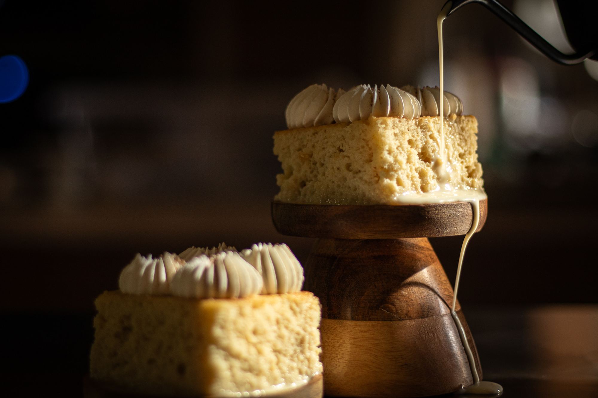 Three milks sauce poured over Cloud Milk cake on a dark wood stand